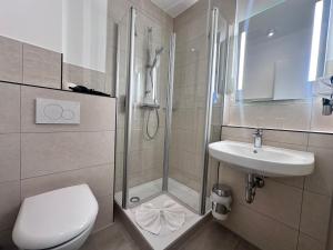 a bathroom with a shower and a toilet and a sink at Hotel Rummeni in Borkum