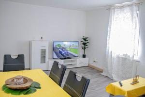 un soggiorno con tavolo da pranzo e TV di F&F Suites Ilsfeld - 3 Zimmer OG Apartment - Zentral mit kostenfreien Privatparkplätzen und WLAN a Ilsfeld