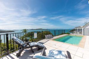 a patio with a swimming pool and chairs and the ocean at Panorama at Shute Harbour in Shute Harbour