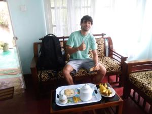 un hombre sentado en un sofá con una bandeja de comida en ohiya colonial bungalow, en Ohiya