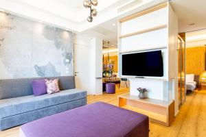 sala de estar con sofá y TV de pantalla plana en Hotel Alexandra - Beach Front -XXL Breakfast & Brunch until 12 30pm, en Misano Adriatico