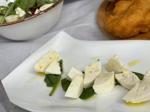 un plato de queso en una mesa con una ensalada en Two Brothers Valbone, en Valbonë