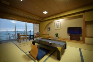 a living room with a table and a view of the ocean at Yura Onsen Yaotome in Tsuruoka