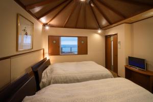 - 2 lits dans une petite chambre avec fenêtre dans l'établissement Yura Onsen Yaotome, à Tsuruoka
