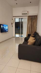 a living room with a black couch and a tv at Masturi Homestay in Chemor