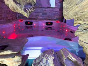a bath tub with red lights in a rock bathroom at Domaine de la Besnerie Gites avec SPA Privatif à 10 min du Mont St Michel in Tanis