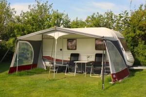 a tent with chairs and a table in a field at Caravan met wijds uitzicht in Kuinre