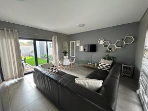 a living room with a black couch and a table at Langebaan Holiday Home in Langebaan