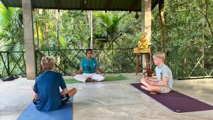 a group of three people sitting in a yoga class at Kandy Eco Retreat in Kandy