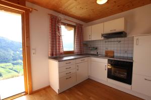 cocina con armarios blancos y ventana grande en Leitl Hütte ZILG100, en Zell am Ziller