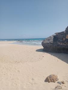 uma praia arenosa com uma rocha na areia em A.M.A Appartament em Calheta Do Maio