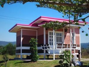 a pink house with chairs in front of it at Bansaunjaisai Resort บ้านสวนใจใส รีสอร์ท in Wang Nam Khieo