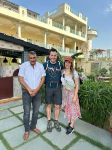 3 persone che posano per una foto davanti a un edificio di Dá Bungalow - A Vacation Abode ad Agra