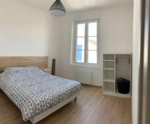 ein weißes Schlafzimmer mit einem Bett und einem Fenster in der Unterkunft Maison de ville avec terrasse in Saint-Denis-dʼOléron