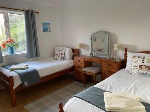 a bedroom with two beds and a desk and a mirror at Cuckoos Rock in Graver