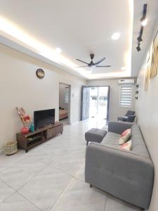 5 Blossom Loveu Homestay في سِريمبان: غرفة معيشة مع أريكة وتلفزيون