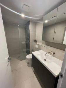 Baño blanco con lavabo y aseo en Spacious 2 bedroom apartment-free parking-pool-gym-wi-fi en Belconnen