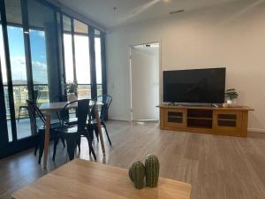 a living room with a flat screen tv and a table at Spacious 2 bedroom apartment-free parking-pool-gym-wi-fi in Belconnen