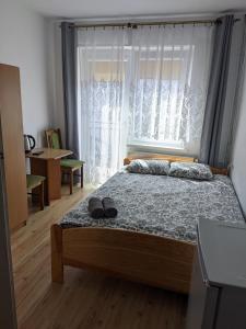Un dormitorio con una cama con una ventana y zapatos. en DELFIN Wynajem Pokoi en Ostrowo