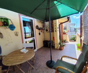 a green umbrella over a wooden table and chairs at Tramonto in Laguna in Càbras