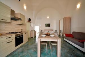 een keuken en een woonkamer met een tafel en een bank bij Mini casa in Salento in Cutrofiano