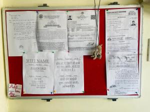 a red bulletin board with papers on it at Aditi home stay in Ujjain
