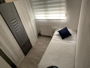 ein kleines Zimmer mit einem Bett mit einem blauen Kissen in der Unterkunft Piso vacacional 7 minutos Cadiz in El Trocadero