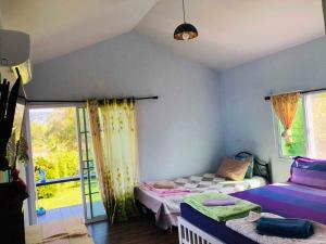 a bedroom with two beds and a window at Bansaunjaisai Resort บ้านสวนใจใส รีสอร์ท in Wang Nam Khieo