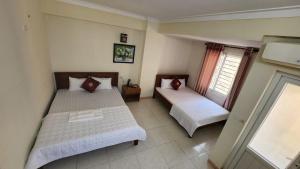 een slaapkamer met 2 bedden en een raam bij Phú Hồng 1 Hotel in Sầm Sơn