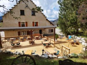 a large house with a deck with chairs and tables at Auberge des Montauds in Villard-de-Lans