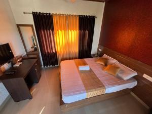 1 dormitorio con 1 cama grande, escritorio y ventana en Hill side Home en Anachal