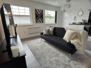 - un salon avec un canapé noir et 2 fenêtres dans l'établissement Cosy 1 Bed Flat with Free Parking, à Birmingham 9 autres photos