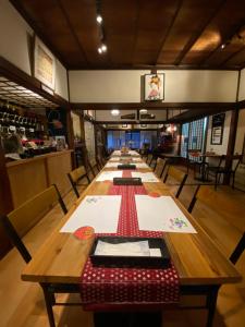 una larga mesa de madera en un restaurante con sillas en Okiya Guest House & Tapas Bar, en Kiryu