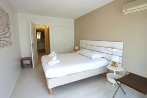 a white bedroom with a white bed and a table at Apartment Seaside in Cannes