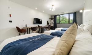 安东市CM Park Hotel的一间卧室，配有两张床、一张书桌和一台电视
