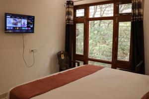 a bedroom with a bed and a tv on the wall at The Tree Lounge in Bhīm Tāl