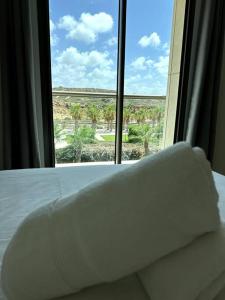 a bed with a pillow in front of a window at Elegant 1 Bedroom Oasis Marina in Herzelia 