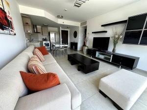 a living room with a white couch and a tv at Elegant 1 Bedroom Oasis Marina in Herzelia 
