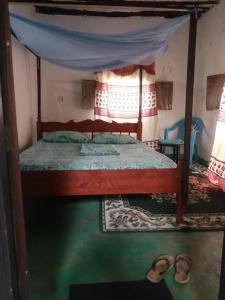 a bedroom with a bed with a canopy and slippers at Tabassam Guest House in Lamu