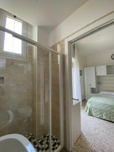 a bathroom with a glass shower and a bed at Hotel Imperiale in Cesenatico