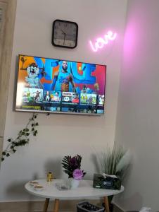TV en la pared con reloj y mesa en Luxor's Studio, en Abu Dabi