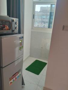 uma cozinha com um frigorífico e um tapete verde em Luxor's Studio em Abu Dhabi