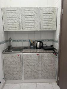 eine Küche mit Edelstahlschränken und einer Spüle in der Unterkunft Luxor's Studio in Abu Dhabi