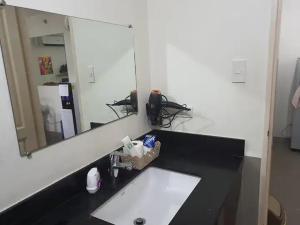een badkamer met een wastafel en een grote spiegel bij Amalfi Oasis SRP in Cebu City