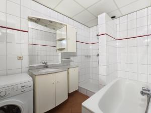 a white tiled bathroom with a sink and a washing machine at Appartement Wijde Blick 1.11 - Callantsoog aan Zee in Callantsoog +7 photos