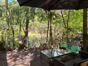 a table and chairs under an umbrella in the woods at Bungalow Biberspur in Zieko