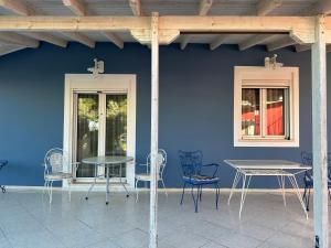 una pared azul con mesas y sillas en un patio en Elenas House, en Kineta