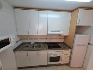 a small kitchen with white cabinets and a sink at Apartamentos Las Palmeras V.v. in La Manga del Mar Menor