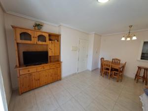 a living room with a television and a dining room at Apartamentos Las Palmeras V.v. in La Manga del Mar Menor