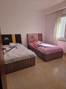 two twin beds in a room with a window at Appartement proche de la plage à 200 M restaurant Piccolino in Dar el Koudia